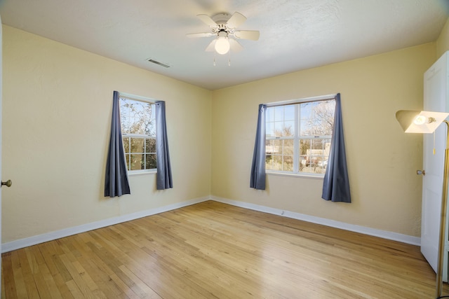 unfurnished room featuring visible vents, plenty of natural light, light wood-style flooring, and baseboards