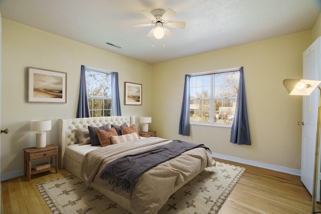 bedroom featuring light wood finished floors, multiple windows, visible vents, and baseboards