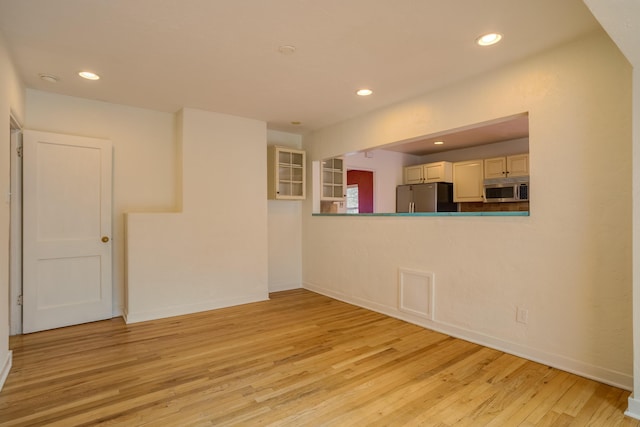 empty room featuring baseboards, light wood-type flooring, and recessed lighting