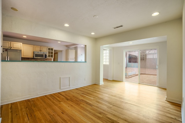 unfurnished living room featuring light wood finished floors, baseboards, visible vents, and recessed lighting