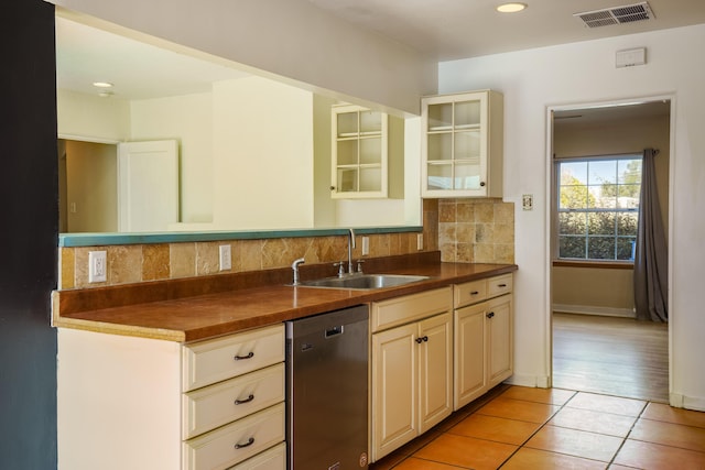 kitchen featuring dark countertops, visible vents, backsplash, a sink, and dishwasher