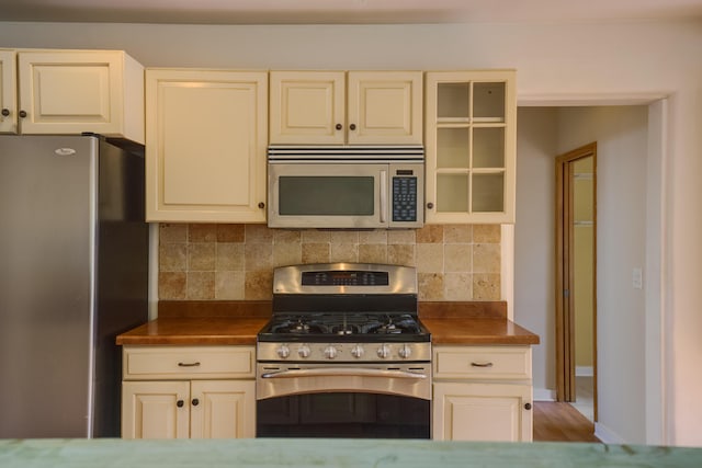 kitchen with stainless steel appliances, backsplash, and cream cabinets