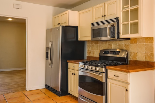 kitchen featuring appliances with stainless steel finishes, dark countertops, decorative backsplash, and cream cabinets