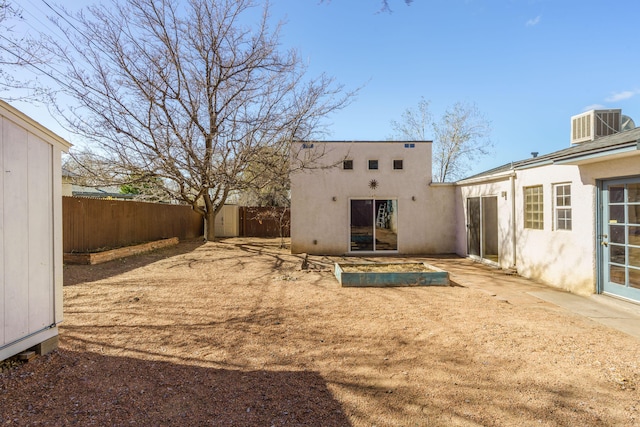 rear view of property featuring cooling unit, fence, and stucco siding