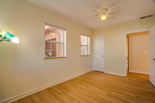 unfurnished room with a ceiling fan, visible vents, baseboards, and wood finished floors