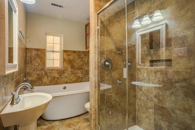 full bathroom with a sink, a shower stall, visible vents, and tile walls