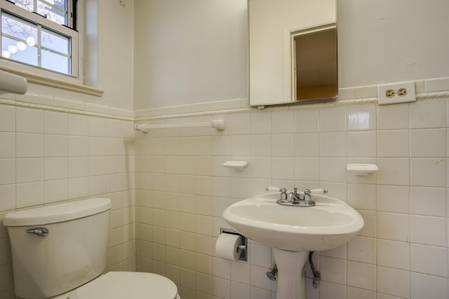 bathroom with wainscoting, tile walls, and toilet