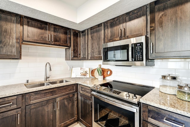 kitchen featuring stainless steel appliances, a sink, dark brown cabinetry, and decorative backsplash