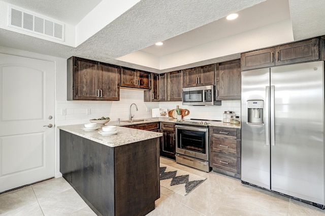 kitchen with stainless steel appliances, visible vents, dark brown cabinetry, and decorative backsplash