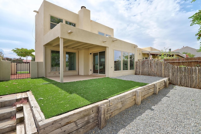 rear view of property with a lawn, a patio area, fence, and stucco siding