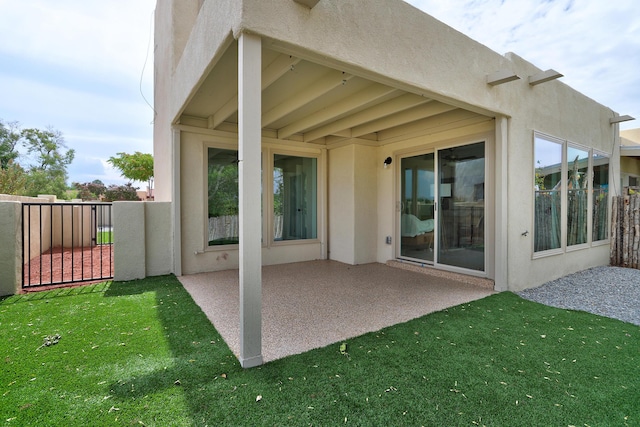 rear view of house featuring a patio area, a yard, fence, and stucco siding