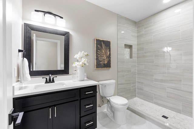 full bath with a tile shower, vanity, and toilet