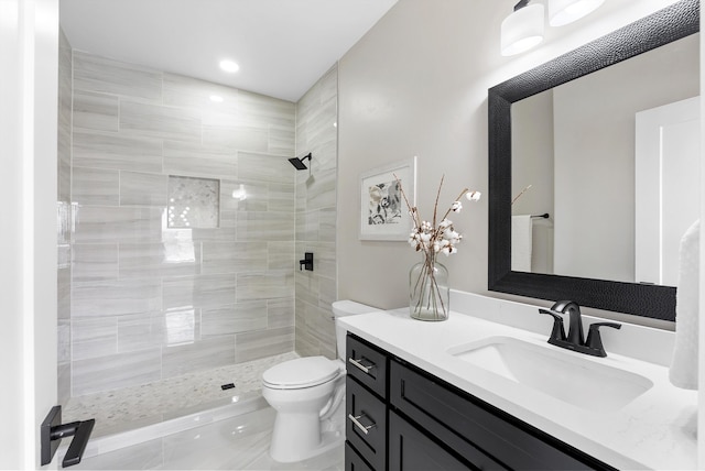 full bath featuring vanity, a tile shower, toilet, and recessed lighting