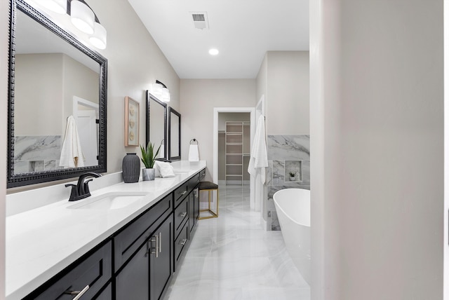 bathroom featuring vanity, visible vents, a freestanding bath, marble finish floor, and a spacious closet