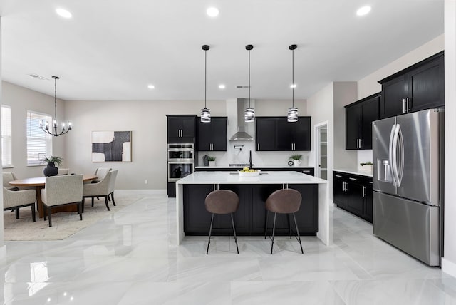 kitchen featuring dark cabinets, stainless steel appliances, a kitchen breakfast bar, light countertops, and wall chimney exhaust hood