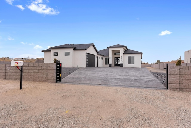 view of front of house with decorative driveway, an attached garage, fence, and stucco siding