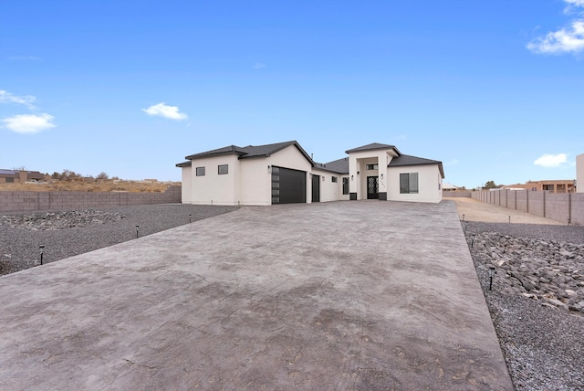 prairie-style home featuring a garage, fence private yard, concrete driveway, and stucco siding