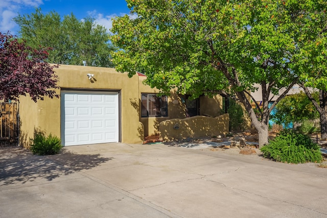 adobe home with concrete driveway, an attached garage, and stucco siding