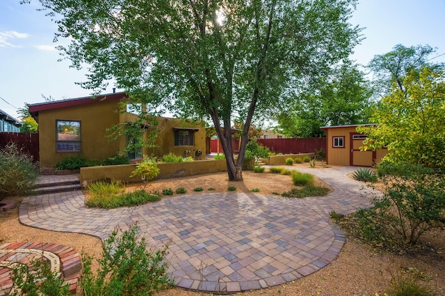 view of patio / terrace featuring a storage unit, fence, and an outbuilding