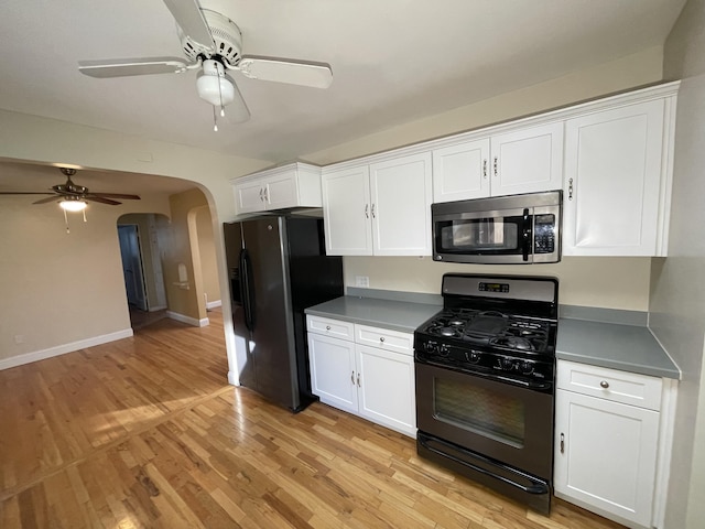 kitchen with arched walkways, white cabinetry, baseboards, light wood-type flooring, and black appliances