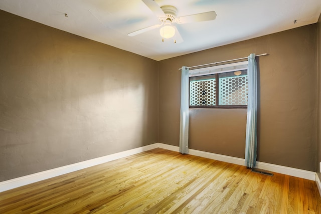 unfurnished room with light wood finished floors, a ceiling fan, and baseboards