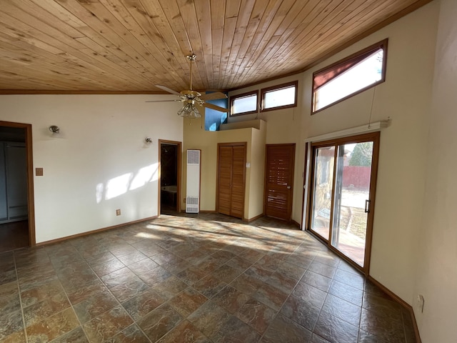 interior space featuring a ceiling fan, wooden ceiling, a towering ceiling, and baseboards