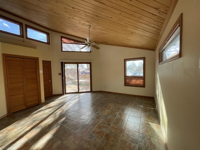 empty room with wood ceiling, a healthy amount of sunlight, vaulted ceiling, and baseboards