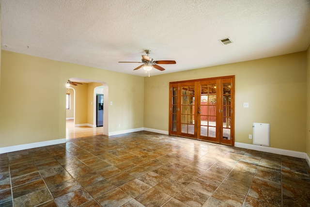 spare room featuring arched walkways, visible vents, ceiling fan, and baseboards