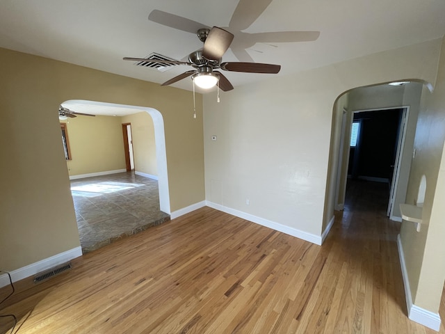 empty room featuring arched walkways, visible vents, and light wood-style flooring