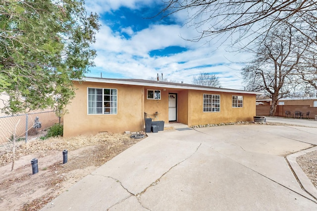 view of front of house with a patio, fence, and stucco siding