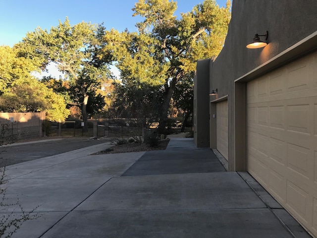 exterior space with a garage, fence, and stucco siding