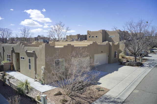 view of home's exterior featuring a garage, driveway, a residential view, and stucco siding