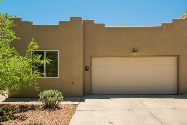 adobe home with driveway, an attached garage, and stucco siding