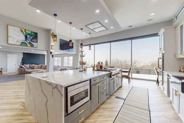 kitchen featuring a spacious island, appliances with stainless steel finishes, light stone counters, gray cabinets, and recessed lighting