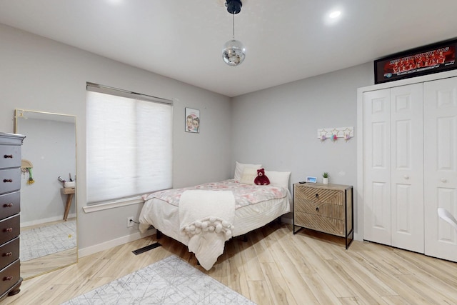 bedroom with a closet, light wood-style flooring, and baseboards