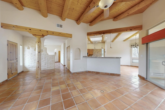 unfurnished living room featuring beam ceiling, light tile patterned floors, visible vents, a chandelier, and wooden ceiling