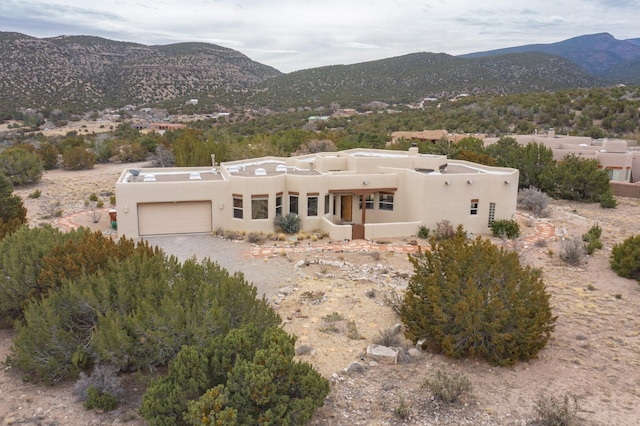 southwest-style home featuring a garage, a mountain view, and stucco siding