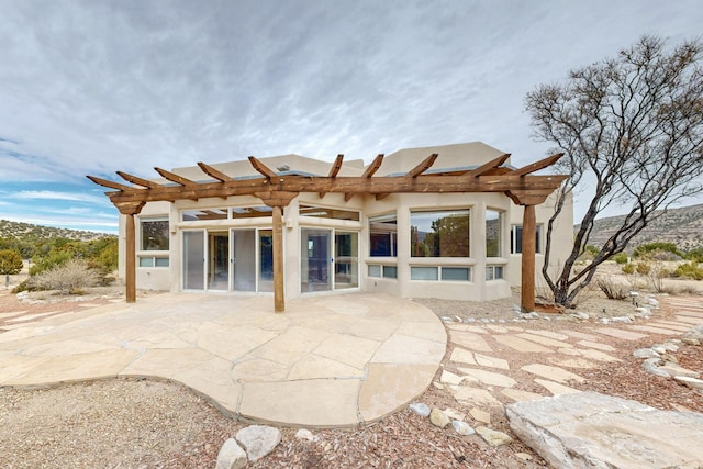 back of house featuring stucco siding, a patio, and a pergola