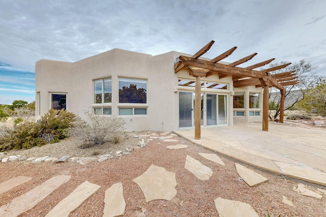 rear view of property with a patio area, stucco siding, and a pergola