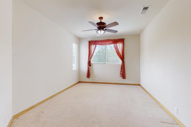 spare room with light carpet, ceiling fan, visible vents, and baseboards