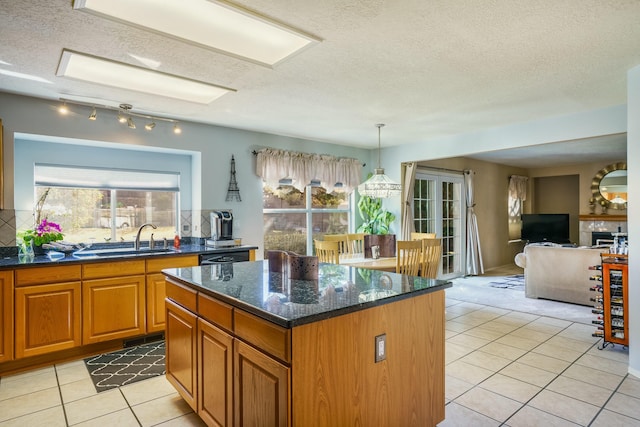 kitchen with brown cabinetry, light tile patterned flooring, a sink, and a center island