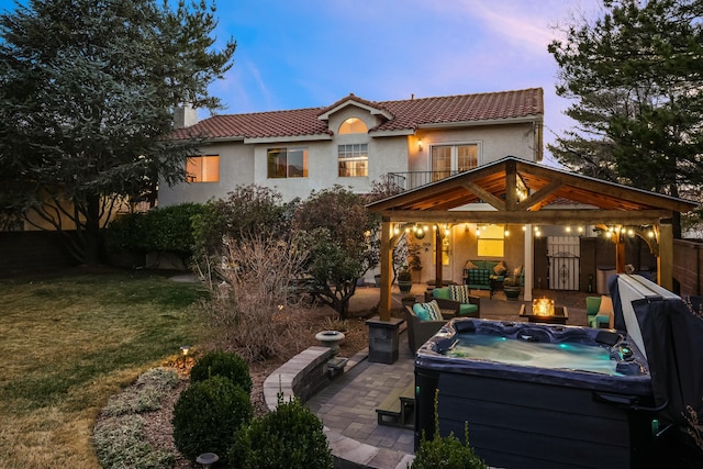 back of house with a hot tub, a patio, a chimney, a tiled roof, and stucco siding