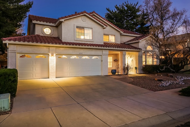 mediterranean / spanish-style home with a tile roof, an attached garage, driveway, and stucco siding