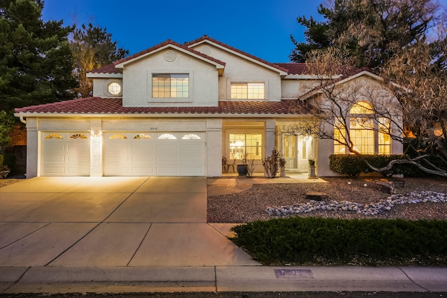 mediterranean / spanish home with concrete driveway, a tiled roof, and stucco siding