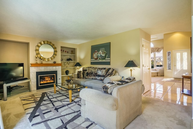 living room with a textured ceiling, a tile fireplace, tile patterned flooring, and built in features