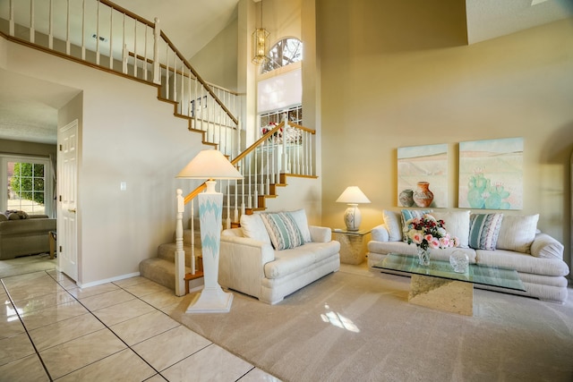 tiled living room with a towering ceiling, stairs, and baseboards