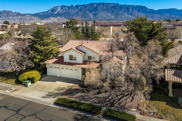 view of front of house featuring stucco siding, a mountain view, concrete driveway, and a tiled roof