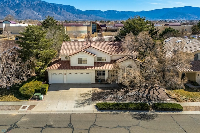 mediterranean / spanish-style house with driveway, a garage, a tiled roof, a mountain view, and stucco siding