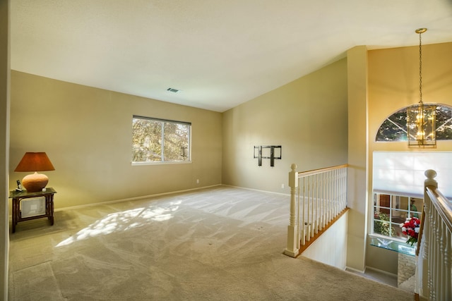 carpeted spare room with vaulted ceiling, visible vents, a notable chandelier, and baseboards