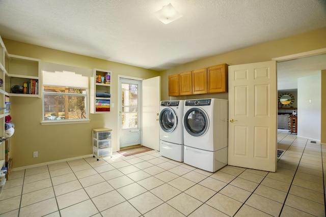 clothes washing area with cabinet space, washer and clothes dryer, a textured ceiling, and light tile patterned floors